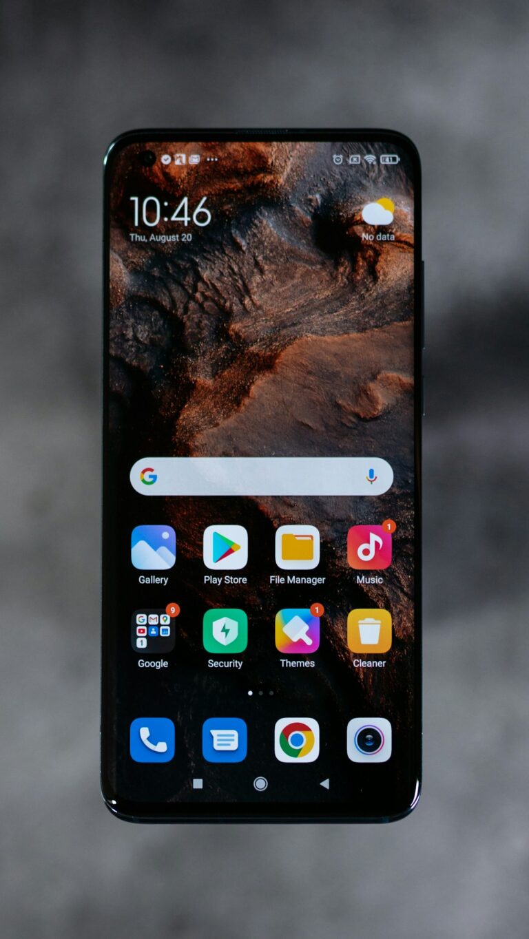Close-up of premium Android smartphone on a clean wooden desk showing AMOLED interface