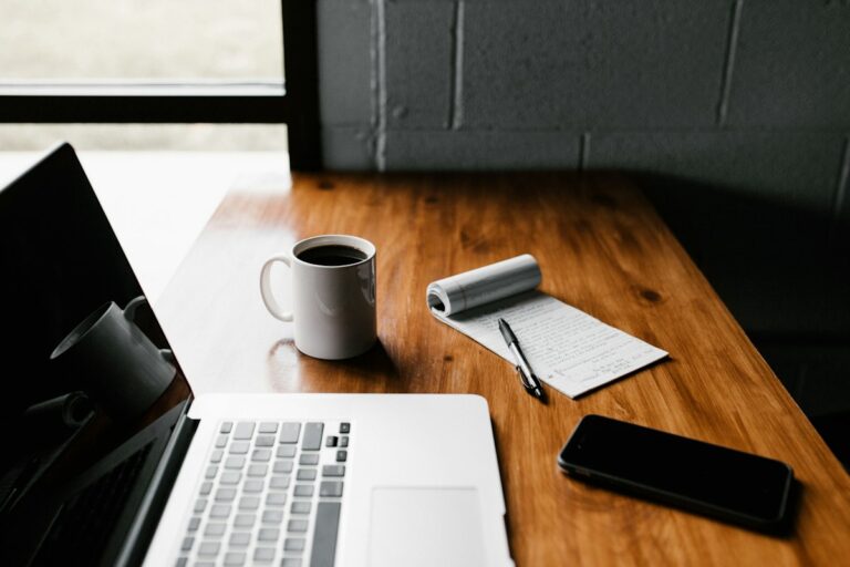 Minimalist laptop workspace with notebook and coffee cup