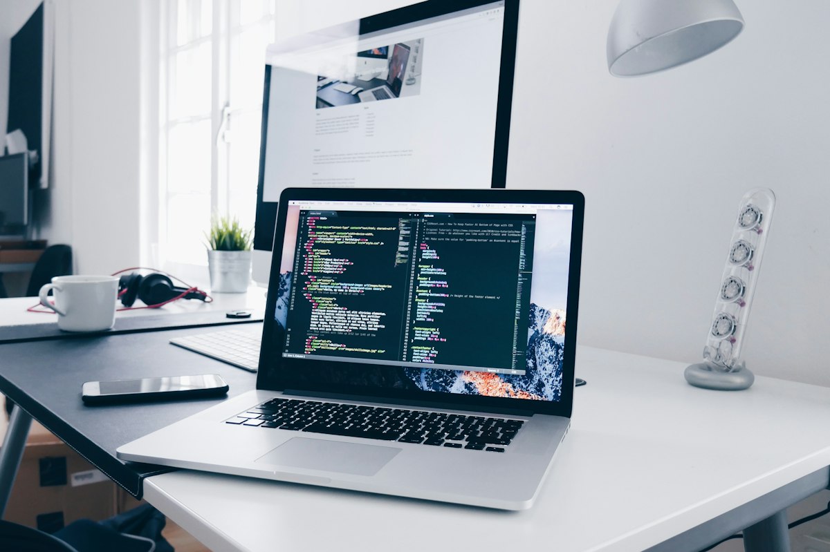 Real photo of a laptop displaying code and workflow scripts on an organized office desk